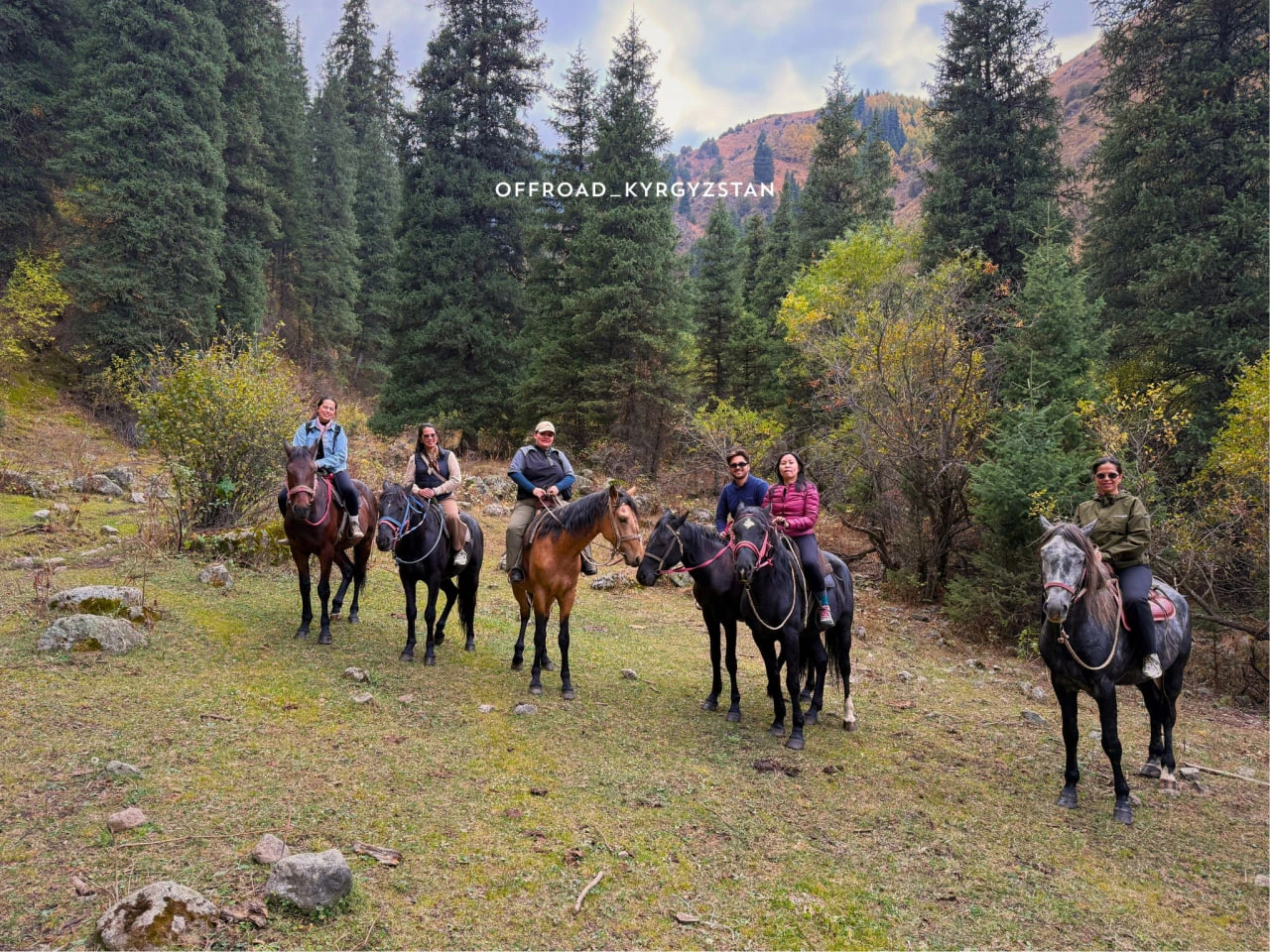 A group of travelers enjoying an organized horseback riding expedition through the mountain passes of Kyrgyzstan.